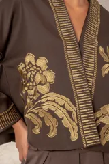 Chaqueta corta estilo kimono color chocolate, con bordados florales en tono dorado en el frente y las mangas. Presenta guardas decorativas bordadas a lo largo del cuello, la apertura frontal y los puños.