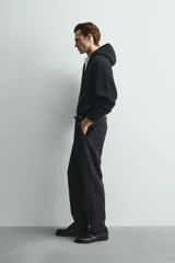 Chaqueta de punto compacto con capucha, confeccionada en hilatura con lana. Presenta cierre frontal con cremallera, mangas largas y acabados en rib.