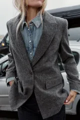 Blazer de corte sastrero confeccionado en tejido de lana con diseño de espiga. Presenta cuello con solapas, hombreras, cierre frontal con un botón y bolsillos delanteros con solapa.