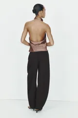 Pantalón negro de tiro alto, corte amplio estilo balloon o culotte, con pliegues marcados en el delantero y bolsillos laterales ocultos.