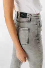 Jean azul claro de corte flare con aberturas en los tobillos y detalles rotos en las rodillas y muslos.