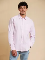 Camisa de corte regular fit, confeccionada en tejido oxford de algodón. Presenta cuello clásico, cierre frontal con botones y un bolsillo en el pecho.