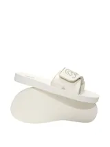 Sandalias de tipo chinela en color blanco marfil, con tira ancha ajustable con velcro satinado y detalle de cristales bordados.