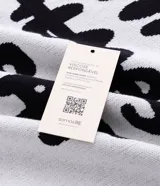 Suéter de corte boxy confeccionado en tejido jacquard de viscosa y poliéster. Presenta cuello redondo, mangas largas y un diseño estampado con lettering en color negro sobre fondo blanco.