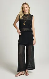 Pantalón calado negro de Le Lis Blanc, con tejido de punto transparente, corte ancho y cintura asimétrica con superposición frontal.