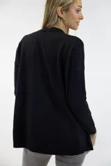 Buzo de punto negro, con cuello redondo, mangas largas y dobladillo asimétrico con aberturas laterales.