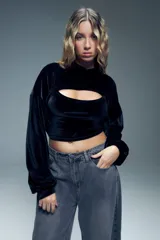 Canguro corto negro de terciopelo con capucha, mangas largas abullonadas con puños elastizados y abertura en el pecho.