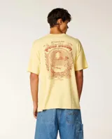 Remera de manga corta color amarillo ocre, corte holgado y diseño con estampa gráfica en el pecho y en la espalda.