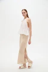 Top blanco de algodón con cuello halter, diseño holgado y detalle de encaje en el borde inferior.