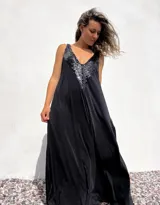 Vestido largo de corte holgado en color negro, con escote en V profundo decorado con lentejuelas negras brillantes. Presenta un diseño sin mangas y una caída fluida.