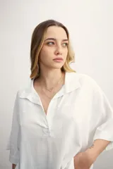 Blusa de lino blanca con cuello polo, escote en V y mangas tres cuartos de corte holgado.