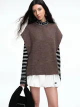 Chaleco de tejido de punto con lana y alpaca, de corte relajado y caída recta. Presenta laterales abiertos con cierre de botones y cuello redondo.