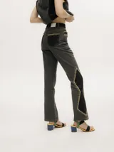 Pantalón de jean tiro alto con corte ochentoso y terminación oxford. Presenta paneles laterales en contraste y costuras decorativas en color amarillo a lo largo de las piernas.