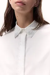 Camisa blanca de algodón con cuello clásico y detalle de brillos en cuello y centro.