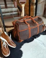 Bolso de mano de viaje de cuero engrasado marrón con detalles en gamuza tostada, asas dobles y cierre superior.