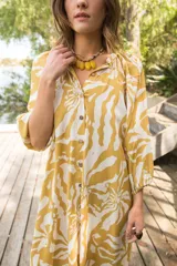 Vestido midi de corte camisero con estampado floral en tonos verde agua y crema. Presenta cuello a la base, cierre frontal con botones y mangas al codo con terminación elástica.