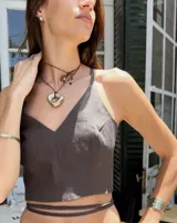 Collar tipo choker con cordón de algodón negro y dije central de metal con forma orgánica irregular y acabado brillante.