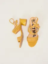Sandalias de gamuza color mostaza, con taco cuadrado de charol, tiras cruzadas en el empeine con detalles de bordado artesanal y correa fina ajustable al tobillo.