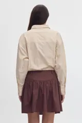 Falda corta de algodón color negro, con volados, cartera de botones frontal y diseño de tiro alto con corte curvo en la cintura.