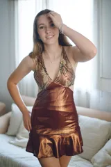 Vestido corto negro con estampado de plumas doradas, escote en V, breteles finos cruzados en la espalda, cut-outs laterales y volado en el ruedo.