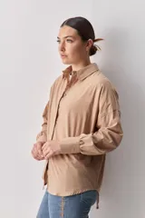 Camisa celeste de corte oversize, con mangas largas, cuello camisero y cierre frontal de botones.