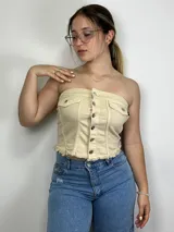 Top strapless color beige con botones plateados al frente y dos bolsillos pequeños.