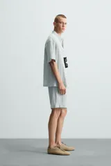 Bermuda negra de corte regular, confeccionada en tejido jacquard con efecto arrugado. Presenta cintura elástica ajustable con cordón blanco, bolsillos laterales y bolsillos traseros de vivo.