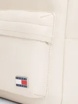 Mochila Tommy Jeans color crema, de poliuretano, con cierre de cremallera, asa superior y correas ajustables y acolchadas. Tiene un compartimento principal, un bolsillo interior de malla y un bolsillo exterior con cremallera.