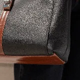 Bolso tipo tote de cuero color marrón con detalles en negro. Tiene doble asa de hombro y correa extraíble regulable. Incluye cierre principal y bolsillo interior.