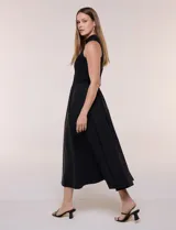 Vestido midi sin mangas de color verde militar, confeccionado con la parte superior en tejido de punto acanalado con cuello alto y falda acampanada de gran vuelo.