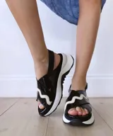 Sandalias negras de cuero con plataforma blanca y detalle de onda blanca en el empeine.