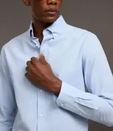 Camisa de manga larga en tejido oxford de algodón color blanco, con cuello tradicional y cierre frontal de botones.