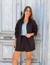 Conjunto de dos piezas color negro compuesto por una camisa de manga larga con botones frontales y un short de tiro alto con cintura elástica.