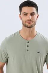 Remera básica de manga corta y cuello redondo en color verde militar, con cartera frontal de tres botones y pequeño bordado en el pecho.