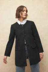 Tapado largo color crema, de paño, con cuello a la base y botones redondos veteados.