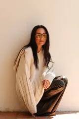 Buzo de tejido de punto color crudo, con cuello amplio que puede usarse caído sobre los hombros, mangas largas con trenzas de ochos y cuerpo con punto arroz.