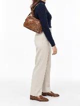 Cartera de cuero vacuno en color marrón, de diseño compacto, líneas simples y formato estructurado. Cuenta con correa corta ajustable para llevar al hombro y cierre superior.