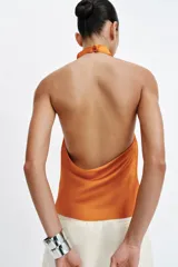 Top de cuello halter satinado en color naranja tostado, con espalda descubierta y cierre trasero de botones.