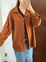 Campera de corduroy color terracota, de corte oversize, con cuello camisero, mangas largas y cierre frontal con botones.