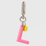 Llavero con dije en forma de letra A color rosado y pequeño dije circular amarillo con logo de la marca grabado. Incluye gancho metálico tipo mosquetón.