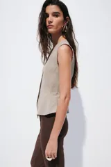 Chaleco sastrero con escote en V, cierre frontal con botones y diseño de peplum acampanado en la cintura. Presenta costuras princesa para un ajuste entallado y se encuentra completamente forrado.