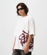 Remera oversized de algodón color blanco, de corte amplio y descontracturado, con cuello redondo, mangas cortas y gran estampa frontal localizada de inspiración urbana en tono bordó.