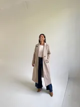 Tapado largo de paño en color beige, con solapas anchas, cierre frontal de un botón y diseño estructurado.