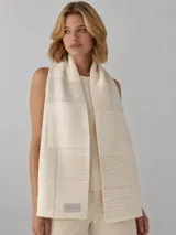 Bufanda de lana 100% natural sin teñir, con diseño patchwork en tonos beige, marrones y blanco, y detalles de líneas horizontales texturizadas.