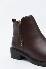 Bota corta de cuero sintético color negro, con taco bajo cuadrado y cierre lateral metálico. Presenta un detalle texturizado tipo reptil en la parte posterior del talón.