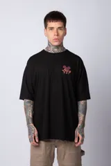 Remera negra de algodón de corte oversize, con mangas cortas y cuello redondo. Estampado pequeño en el frente y diseño grande en la espalda con Mickey Mouse y caracteres orientales en tonos rojizos.