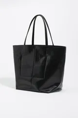 Bolso shopper de tamaño grande confeccionado en cuero reciclado con acabado metalizado plateado. Presenta doble asa superior, costura central vertical y logo de la marca bordado en el frente. Incluye cierre de mosquetón y bolsillo interior.