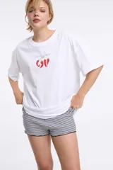 Remera de corte oversized en color blanco, con cuello redondo y mangas cortas. Presenta una estampa central con la frase 'Living a hot life' y un diseño de ajíes rojos.