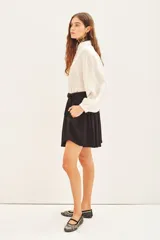 Short negro de tiro alto con pliegues y cinturón con hebilla metálica. El tejido presenta un sutil estampado jacquard.