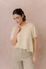Sweater de tejido liviano color crudo, con cuello redondo y mangas cortas de hombros caídos. Presenta líneas horizontales en relieve y calce amplio y relajado.